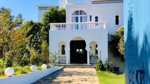 A white building with a stone pathway leading to an arched entrance. - Villa Dar Jbila (Tangier)