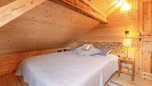 A wooden cabin bedroom with a bed, a nightstand, and a wall-mounted lamp. - Heidi Chalet - Panoramic View - Modern Part (Rossinière)