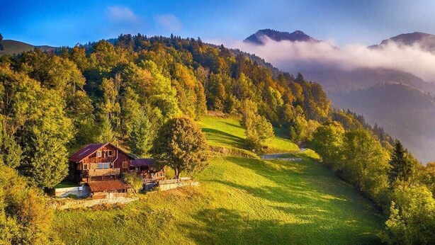 A wooden cabin with a balcony, surrounded by lush green hills and a forested mountain backdrop. - Heidi Chalet - Panoramic View - Modern Part (Rossinière)