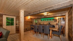 A wooden interior with a dining area, kitchen, and a door leading to a balcony. - Heidi Chalet Alps - Unique Experience - Authentic Part (Rossinière)