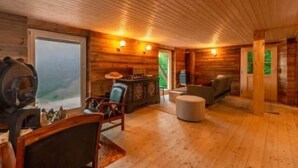 Un interior de madera con techo de madera, un ventanal grande y un área de estar con mesa y sillas.