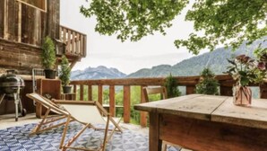 Una terraza de madera con mesa y sillas, una parrilla y plantas en macetas.