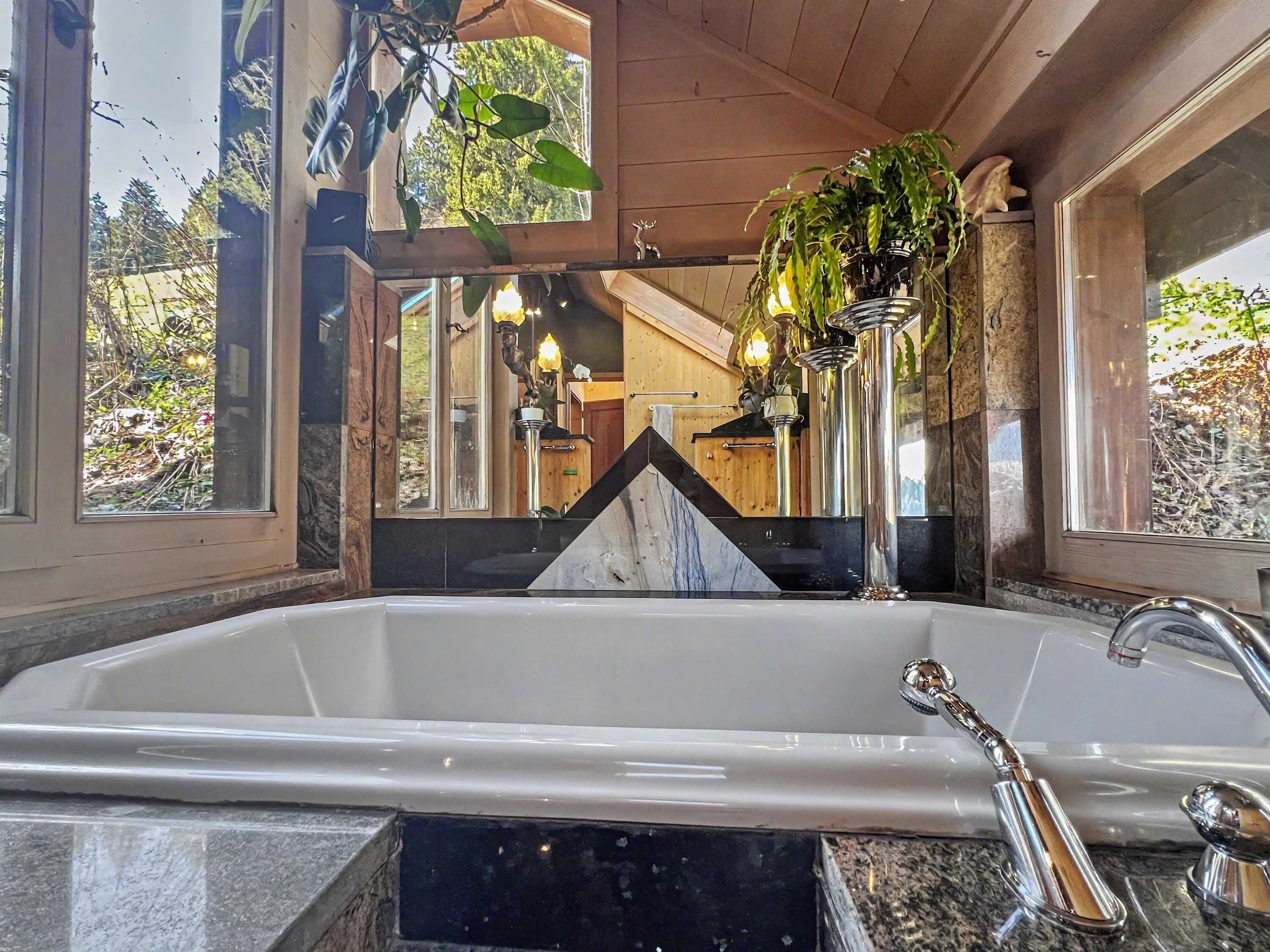 Un baño con una bañera grande, encimera de mármol y techo de madera.