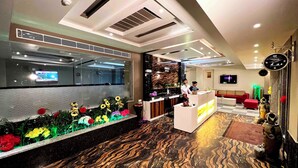 A hotel lobby with a reception desk, a large mirror, and a decorative plant arrangement. - The Shoba Estate Gold (New Delhi)