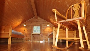 A wooden cabin with a sloped ceiling, a rocking chair, a window, and a bed. - Hjelledalen Hyttesenter (Stryn)