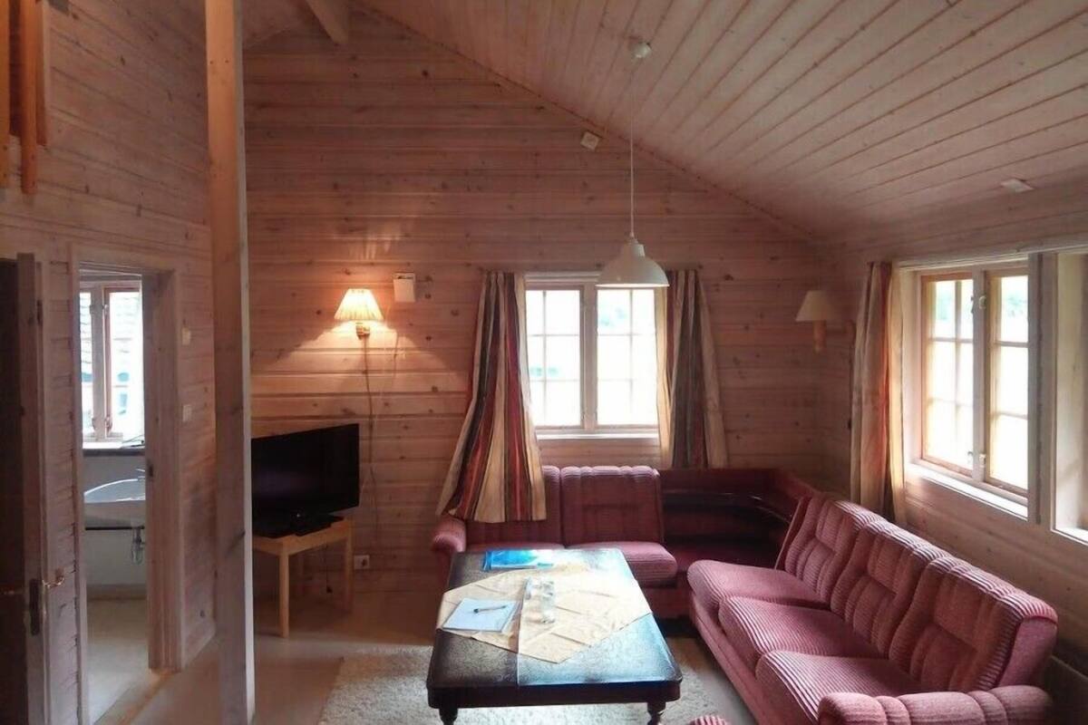 A cozy wooden cabin interior with a television, sofa, and a table with papers.