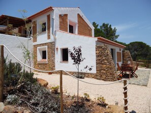 Un edificio de dos plantas con fachada de piedra y sección superior blanca.