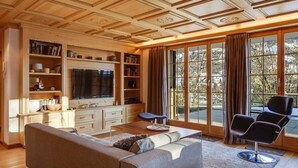 A living room with a sofa, a coffee table, a TV, and a bookshelf.