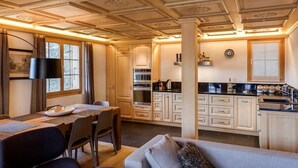 A well-lit kitchen with wooden cabinets, a dining area with a table and chairs, and a modern pendant light.
