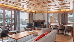 A spacious living room with a fireplace, large windows, and a dining area.