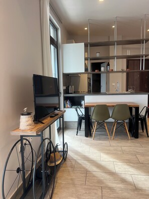 A modern kitchen with a dining area, a TV on a cart, and a wheelchair-accessible table.