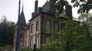 Ein historisches Gebäude mit einem markanten Turm und mehreren Schornsteinen.