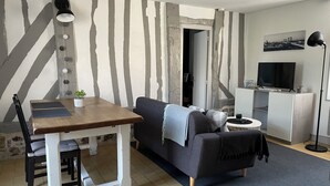 Ein Wohnzimmer mit einer Couch, einem Esstisch und einem Fernseher.