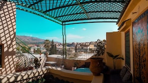 Ein Balkon mit Blick auf eine Stadtansicht, einer Pergola und Kübelpflanzen.