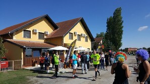 A group of people gathered outside a yellow building with a red roof, possibly at a community event or gathering. - Guest House Vila Alexandar (Palic)