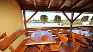 An outdoor wooden table and benches with a view of a lake. - Guest House Vila Alexandar (Palic)