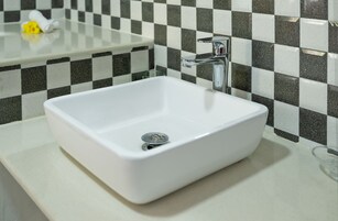 A white rectangular sink with a chrome faucet on a white countertop.