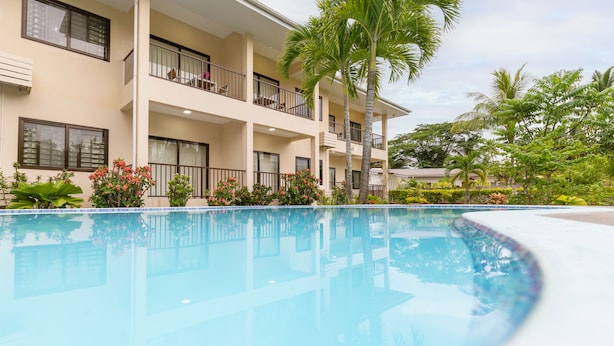 Un hotel con piscina, balcones y jardines tropicales.