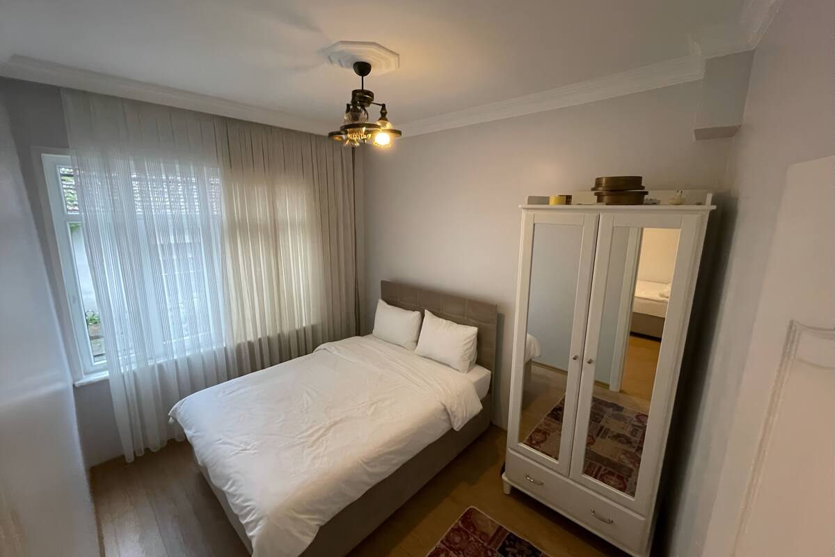Quarto com cama, guarda-roupa e luminária no teto.