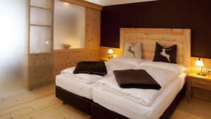 A double bed with white linens, two bedside tables with lamps, a wooden headboard, and a large window with frosted glass. - Hotel Krimmlerfälle (Krimml)