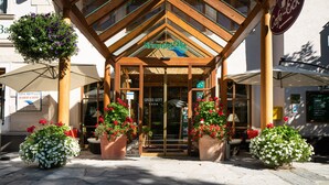A hotel entrance with a wooden facade, large potted plants, and a sign reading "Hotel Krimmerhalle". - Hotel Krimmlerfälle (Krimml)