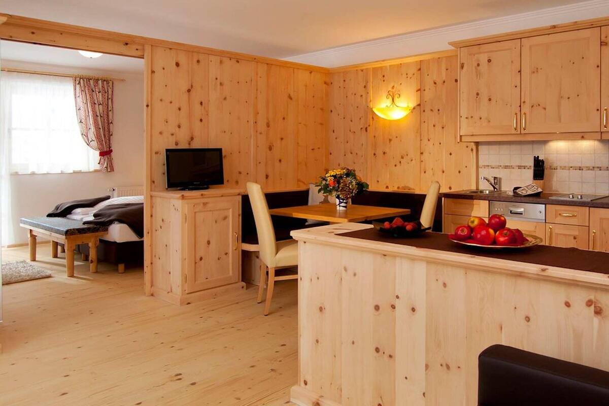 A wooden interior with a dining area, kitchen, and a TV in a corner.