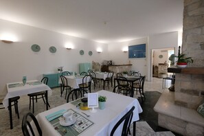 A dining area with multiple tables and chairs, stone walls, and a stone fireplace.