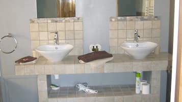 Et badeværelse med to håndvaske, et spejl over hver, og en håndklæderække. Der er toiletartikler på bordet og en måtte på gulvet.