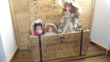 A wooden crate with vintage dolls and a sign reading "LA MINGOR DU PLOM".