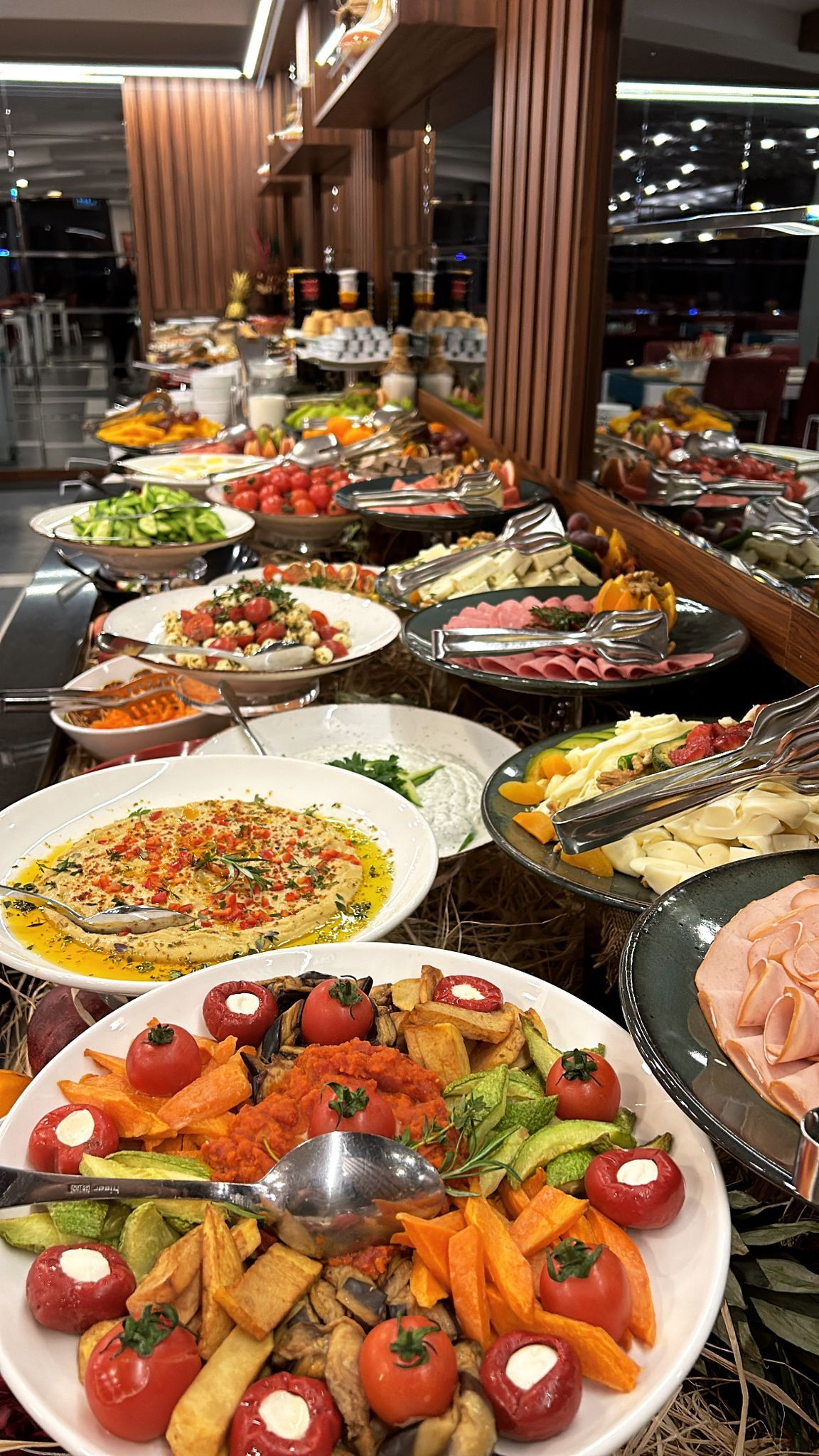 A buffet with various food items including salads, meats, and cheeses.