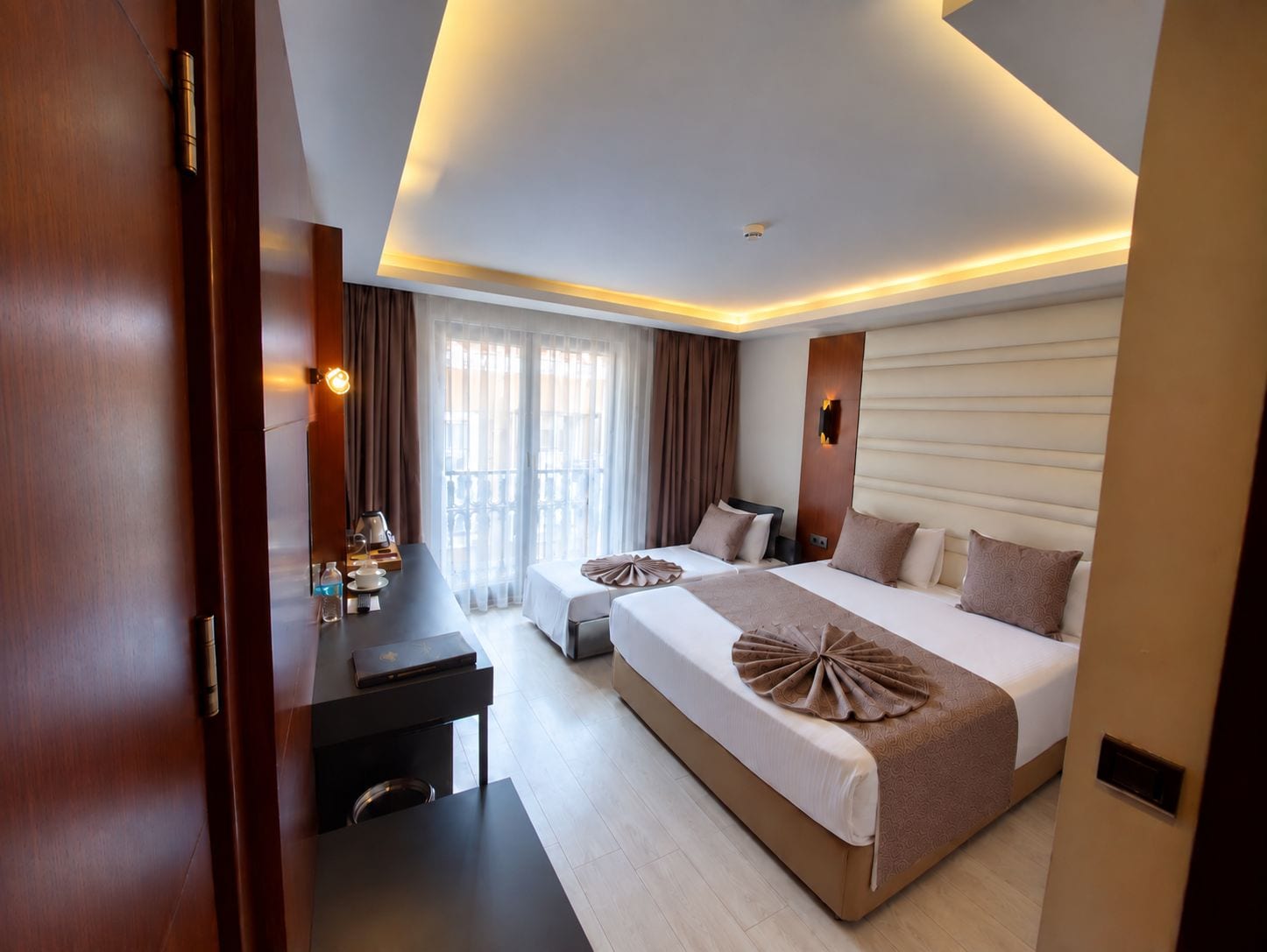 Una habitación de hotel moderna con una cama grande, un escritorio y un balcón con cortinas.