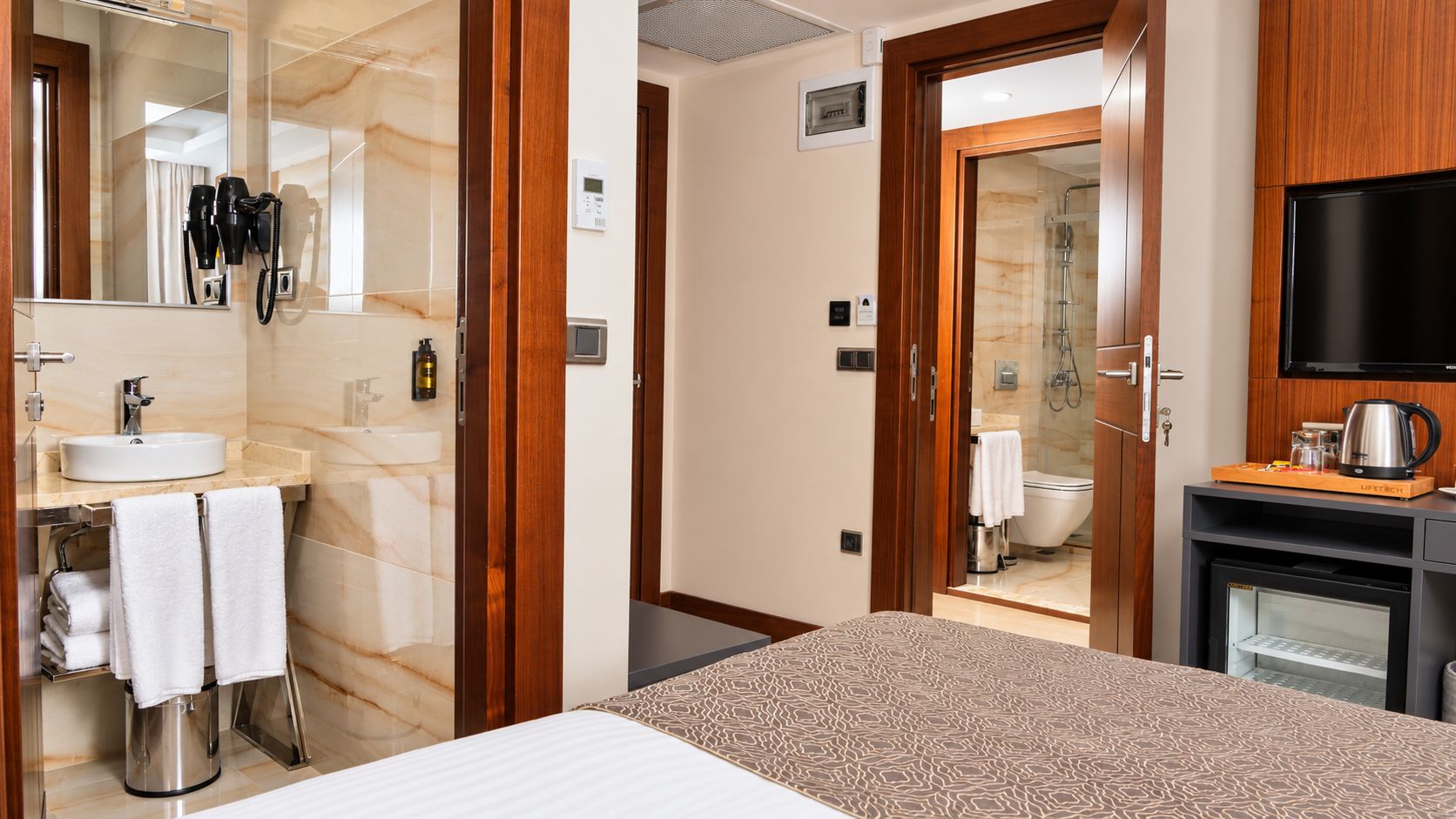 A hotel room with a bed, a bathroom with a sink, a mirror, and a television.