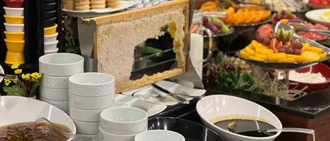 Montaje tipo bufé con diversas opciones de comida, entre ellas frutas, verduras y una selección de bebidas.