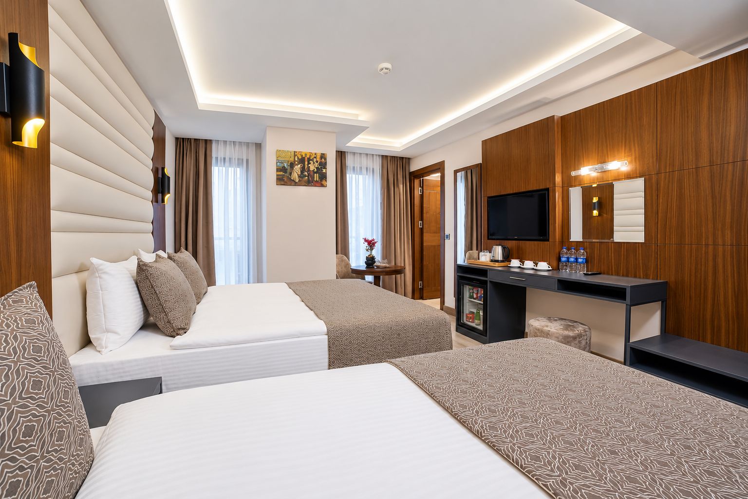Ein Hotelzimmer mit zwei Betten, einem Schreibtisch, einem Fernseher und einer Minibar.