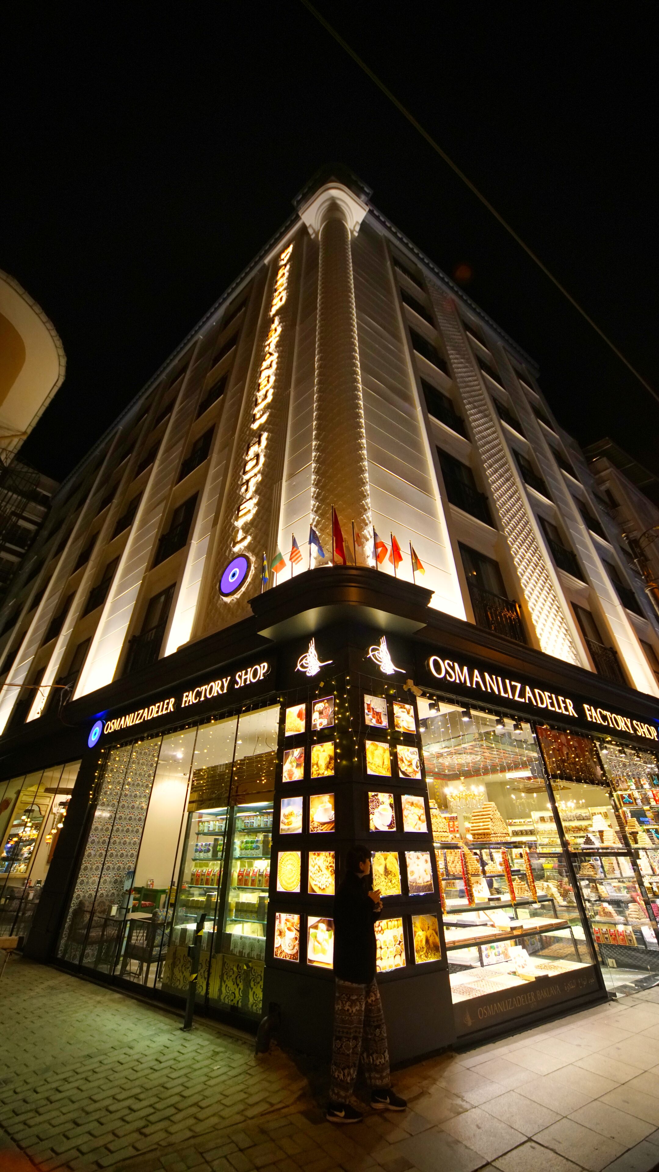 A building with a storefront labeled "OSMANLIZADELER FACTORY SHOP" at night.