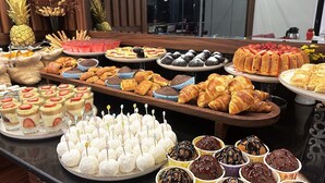Un bufé con diversos postres, incluyendo pastelería, tartas y tartaletas de frutas.