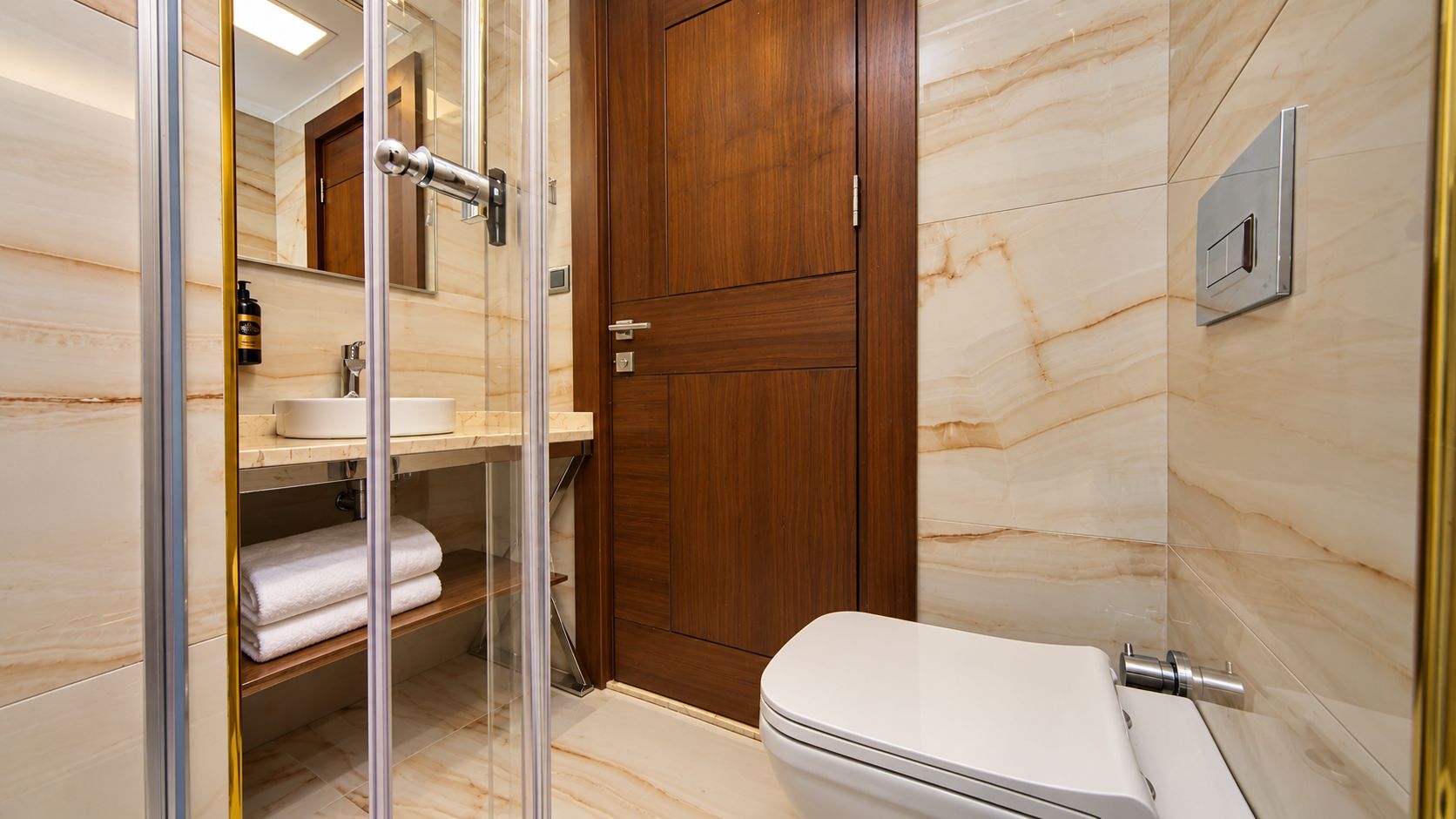 Un baño moderno con ducha envuelta en vidrio, un gabinete de madera y un inodoro blanco.
