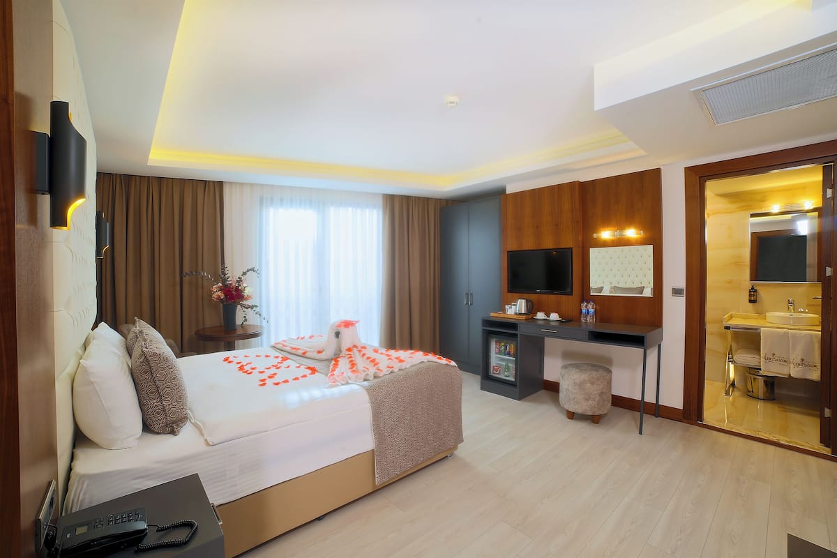 A hotel room with a bed, bedside table, desk, and bathroom.