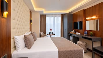 Una habitación de hotel con una cama grande, un escritorio, un televisor y un minibar.