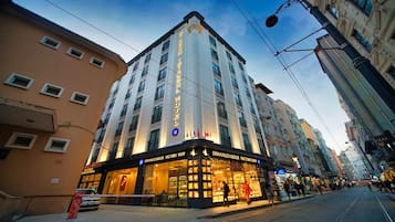 Un hotel con un letrero llamativo, varios pisos y una tienda de fábrica en la planta baja.
