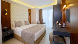 Una habitación de hotel con una cama grande, una mesita de noche y un escritorio con una silla.