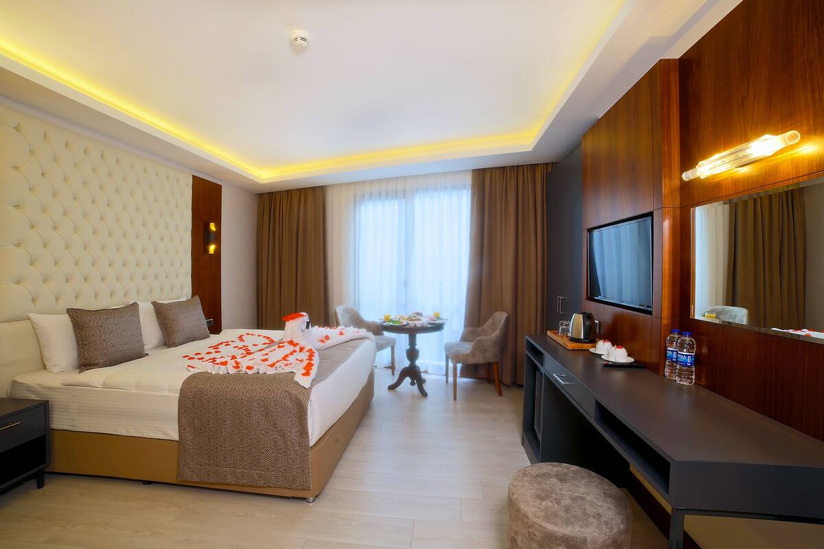 A hotel room with a bed, a desk, a TV, and a dining table with chairs.