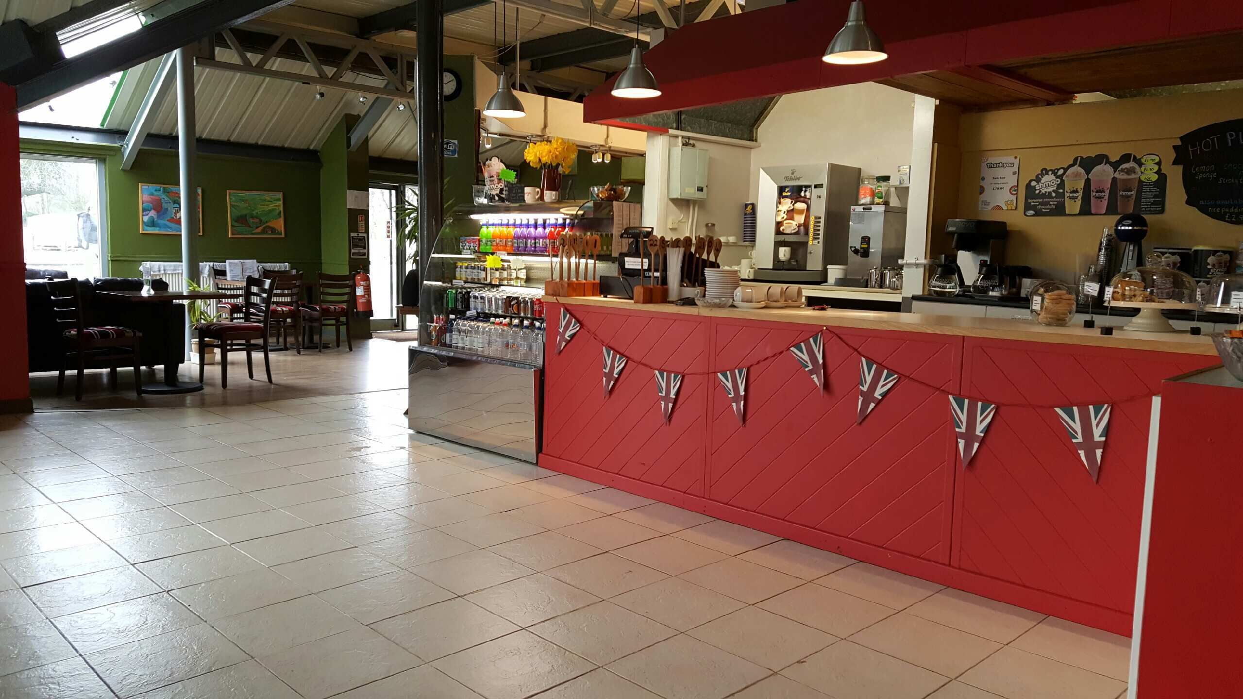 Een café met een rode toonbank, een zitgedeelte en een menubord.