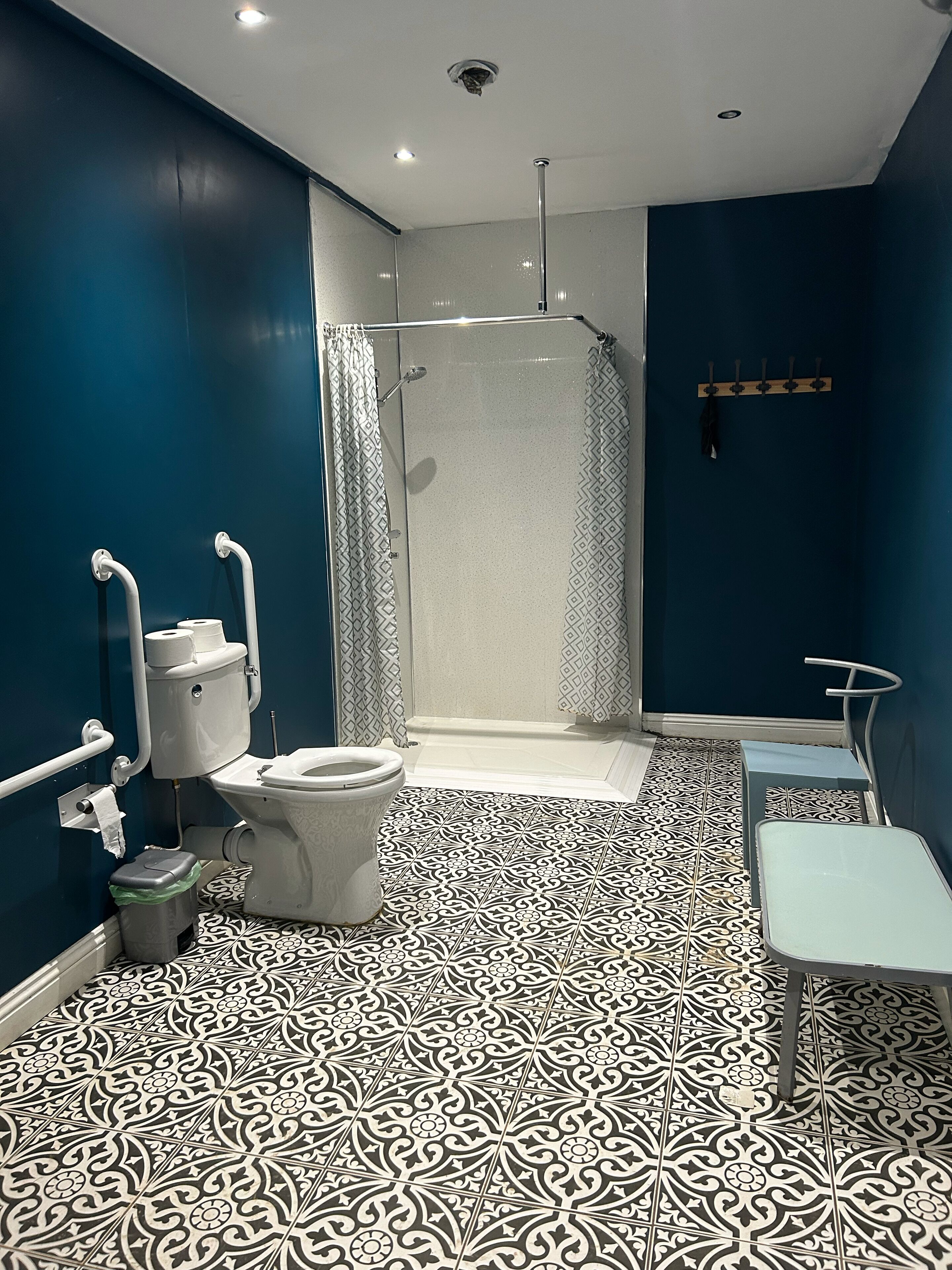 Un baño con inodoro, ducha y un banco.