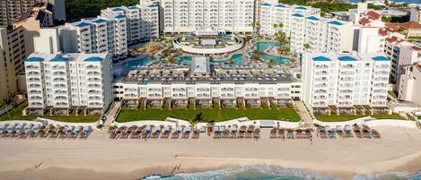 A resort with multiple buildings, a central pool area, and a beach.