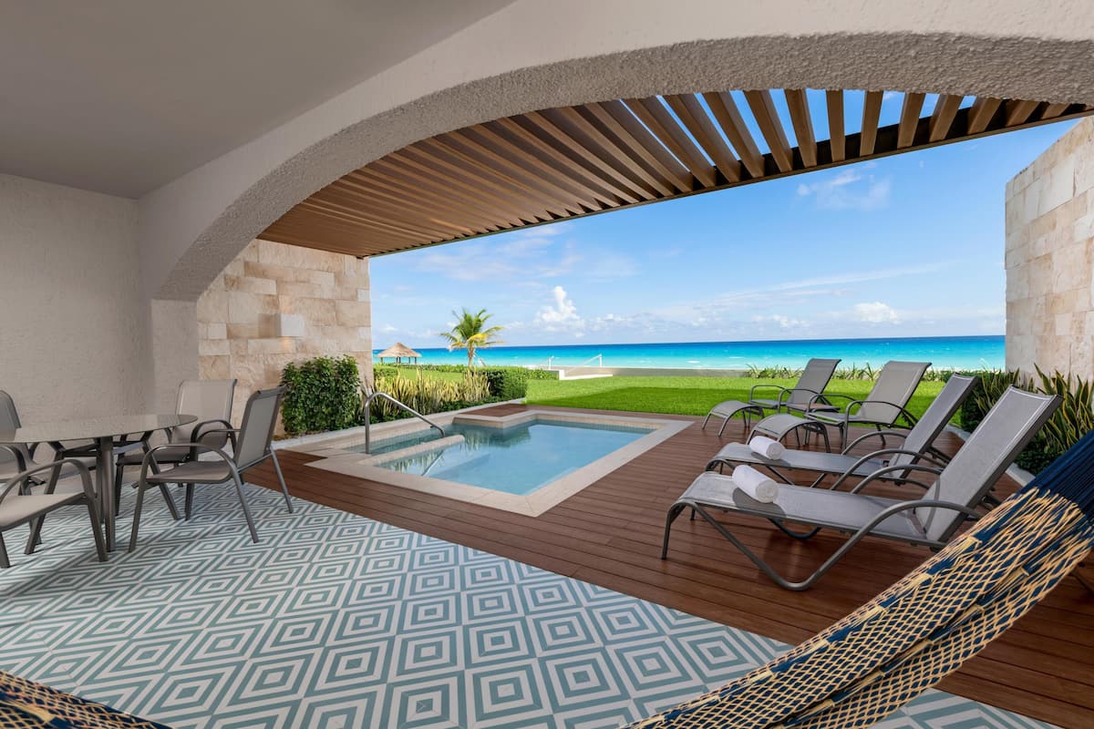 A pool area with a wooden deck, lounge chairs, and a view of the ocean.