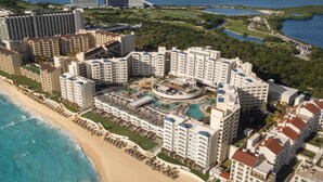 A resort with multiple high-rise buildings, a central pool area, and a beach. - Hilton Cancun Mar Caribe All-Inclusive Resort (Cancun)