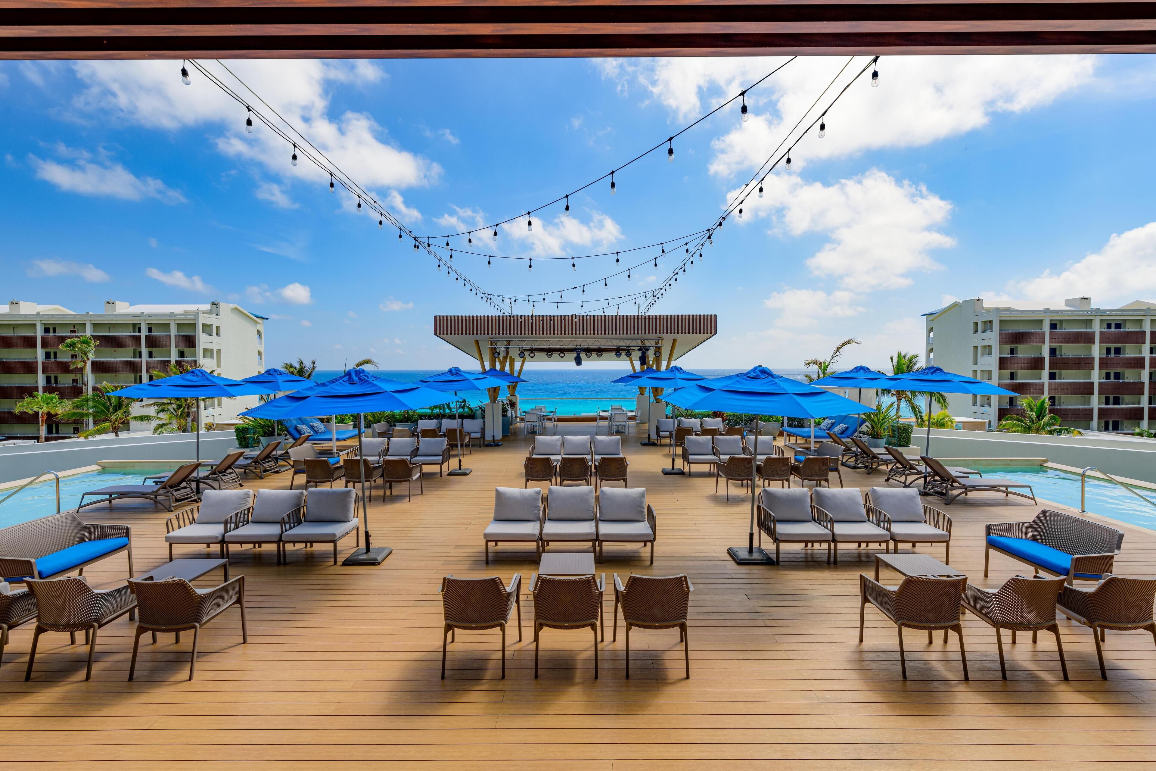 A poolside area with lounge chairs, umbrellas, and a view of the ocean.