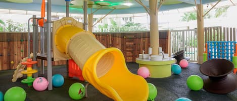 Un área de juegos infantiles con un tobogán, estructuras para escalar y diverso equipamiento recreativo.