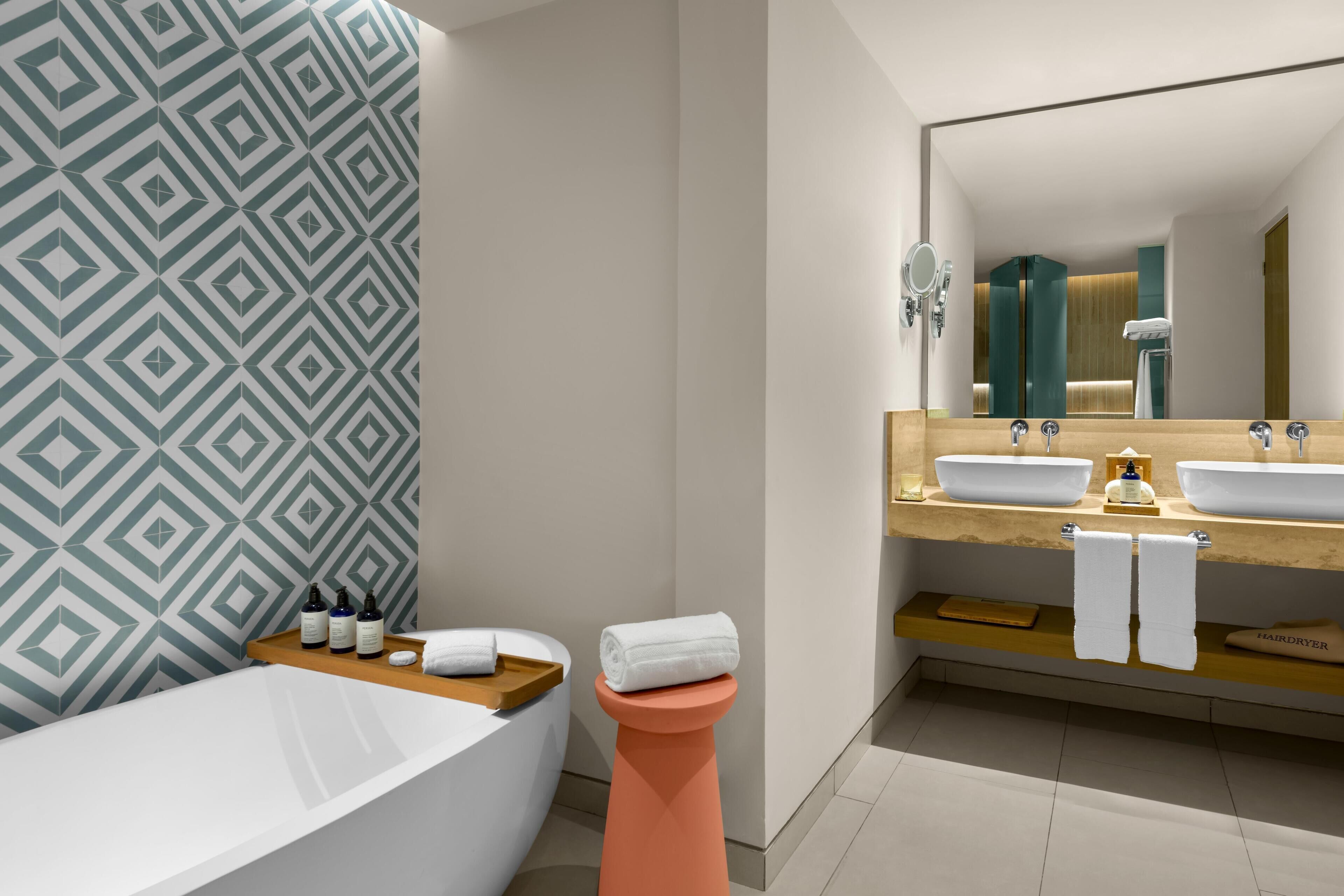 Une salle de bain moderne avec une baignoire sur pieds, un meuble-lavabo avec deux vasques et un grand miroir.